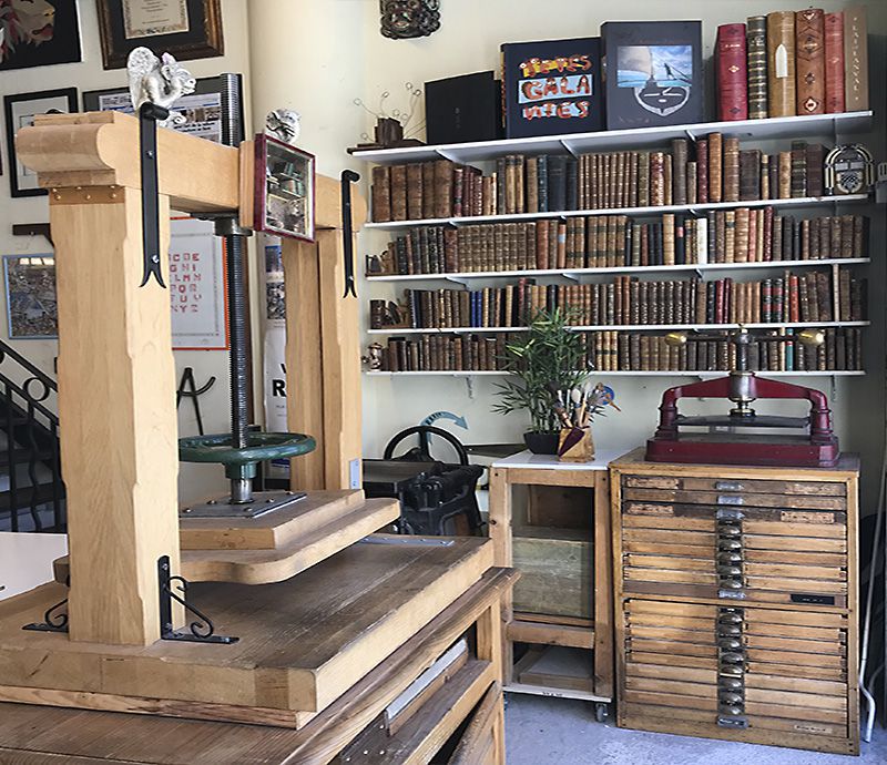 Atelier de relieur d&rsquo;art &agrave; Nice avec presse de reliure et biblioth&egrave;que d&rsquo;ouvrages anciens